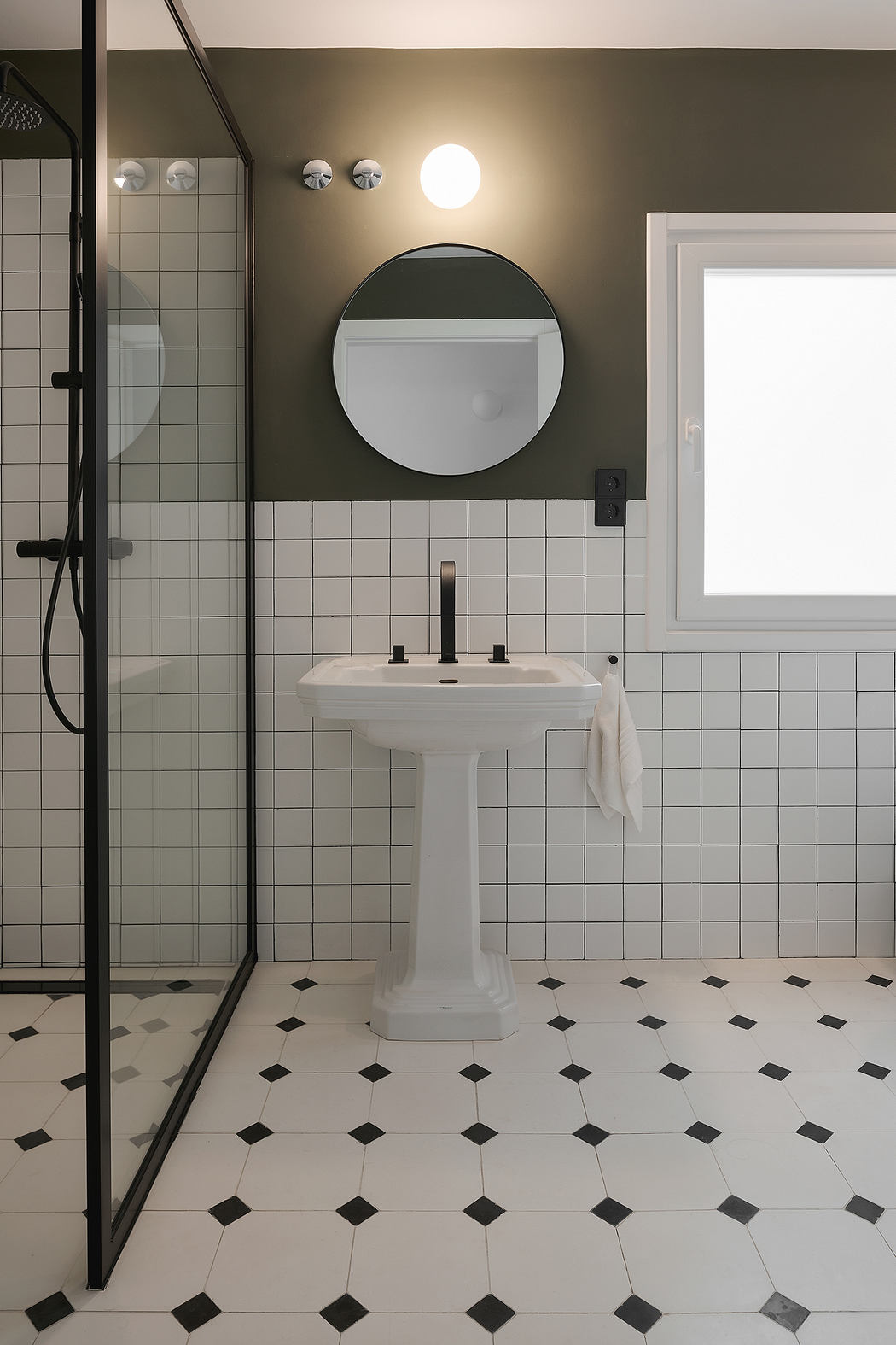 Contemporary bathroom with black and white tiled floor, dark walls, and glass shower