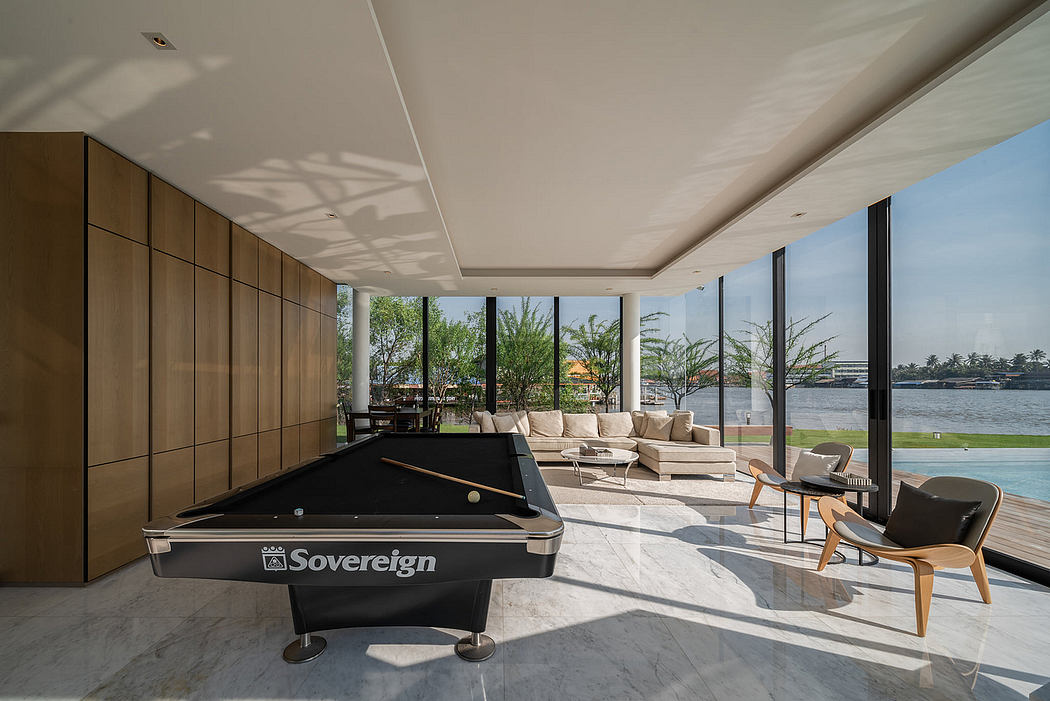 Sleek living room with pool table, large windows, and waterfront view.