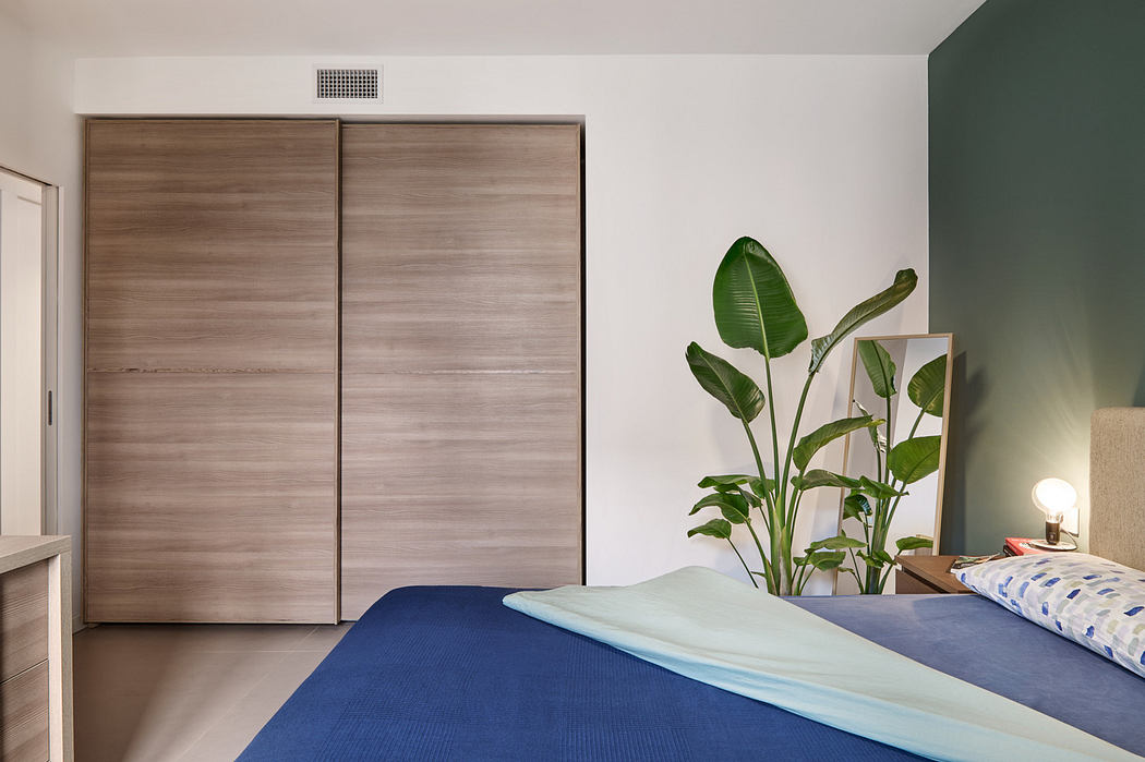 Modern bedroom with large bed, wardrobe, and green plant.