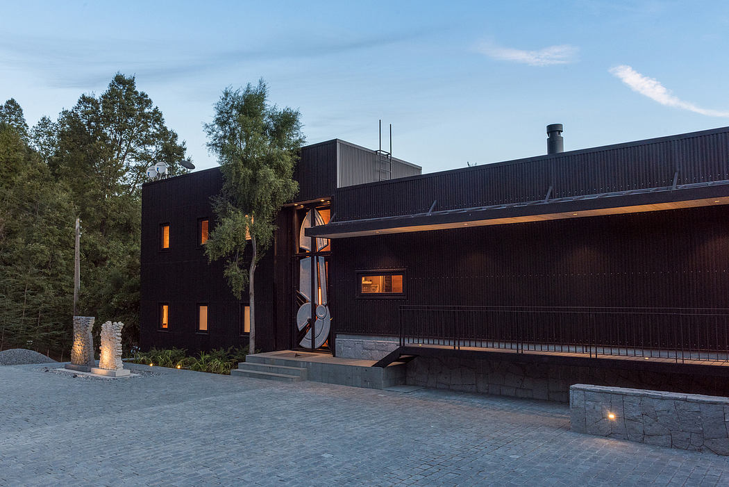 Modern black house with illuminated windows at twilight.