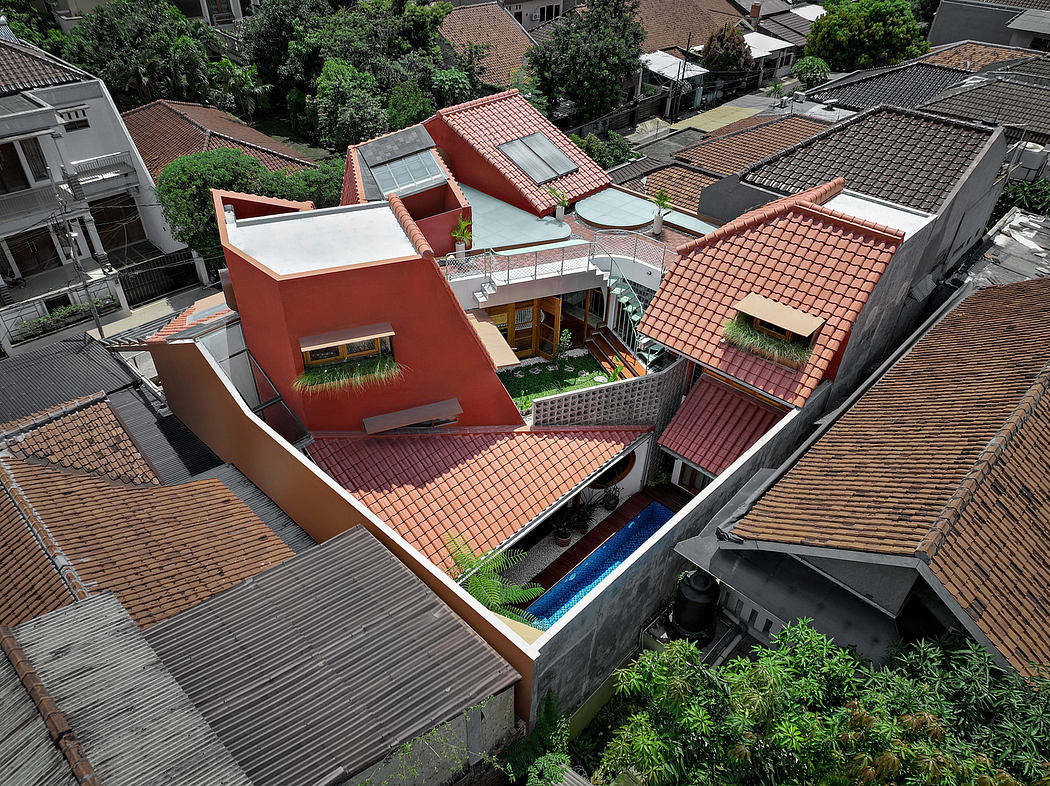 Aerial view of a unique red-roofed house among traditional homes with a