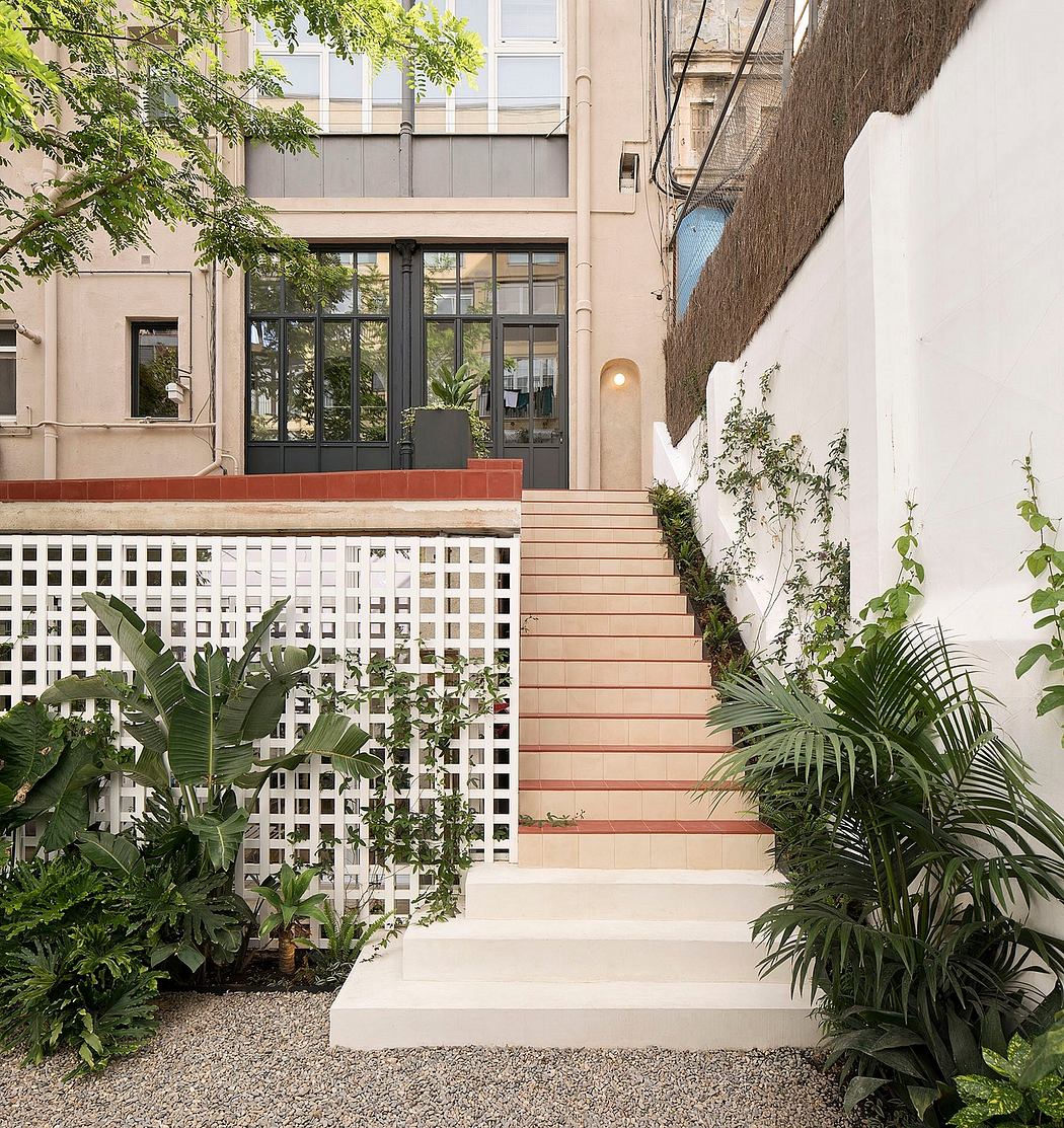 Outdoor staircase with plants and lattice leading to a modern building.