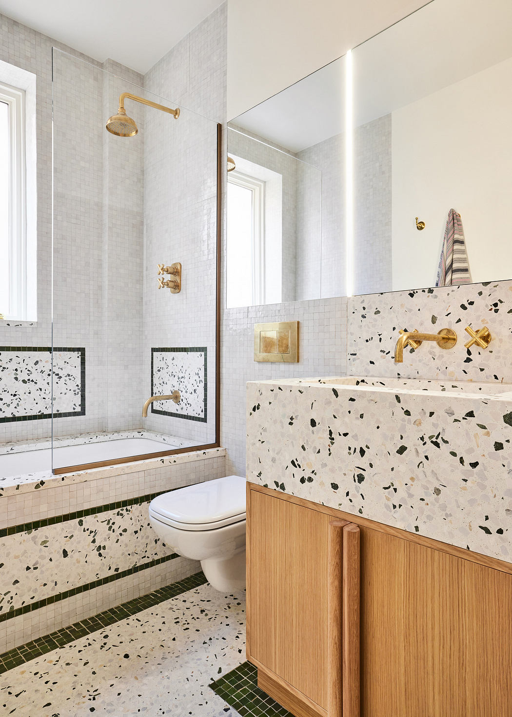 Modern bathroom with terrazzo tiles and wooden cabinetry.