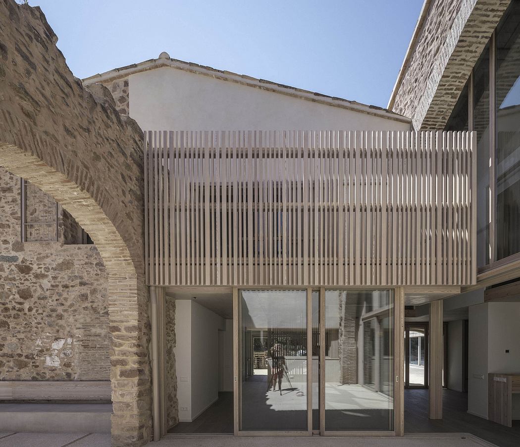 Modern structure with wooden slats integrated into an old stone building.