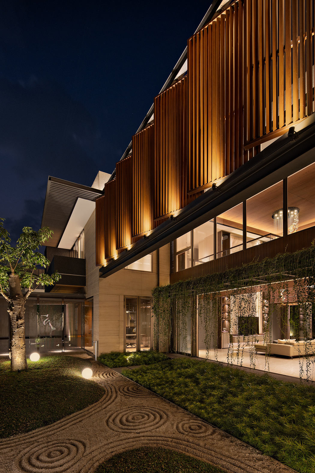 Contemporary house with vertical wooden slats and garden lighting at dusk.