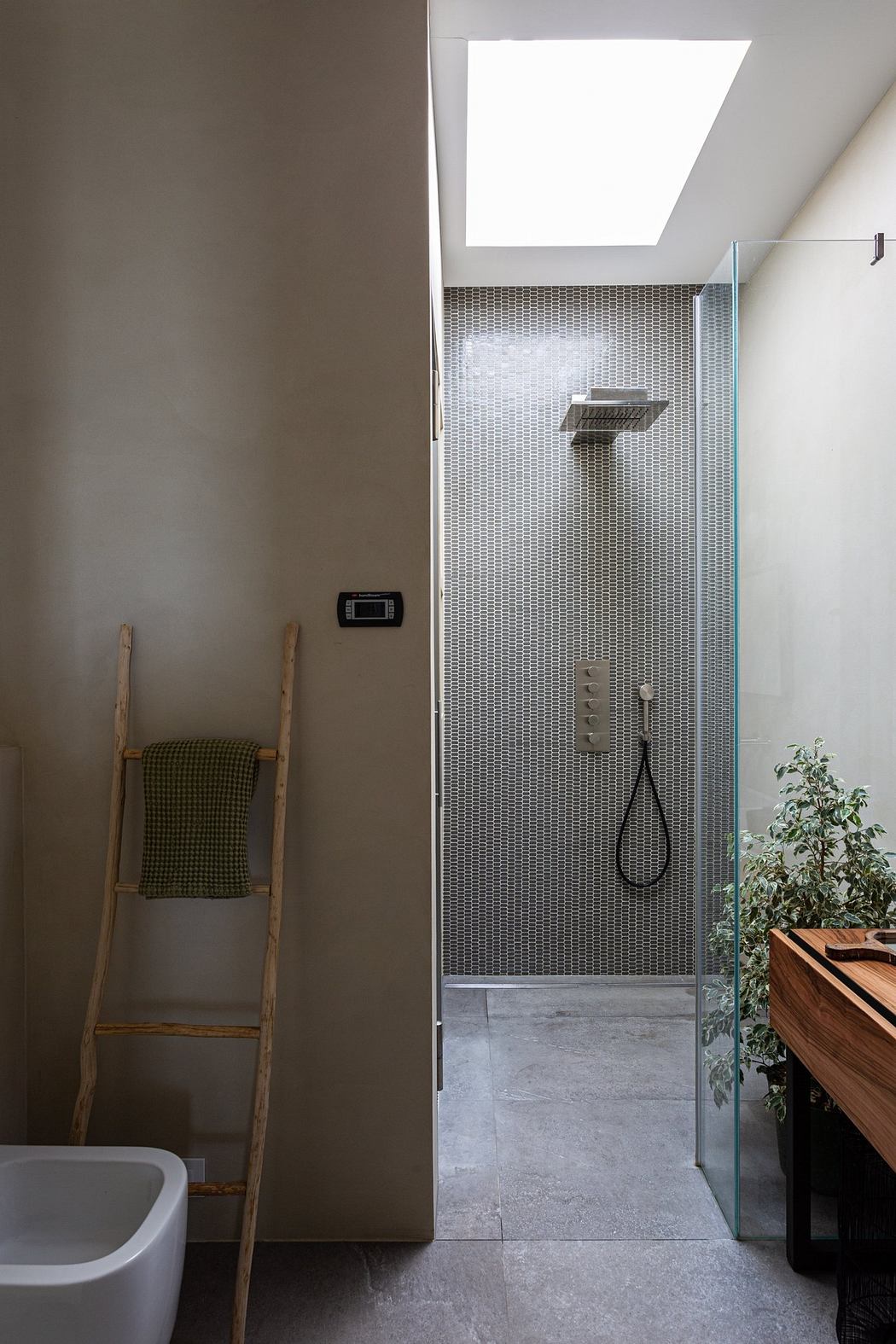 Modern bathroom interior with skylight, glass shower, and wooden accents.