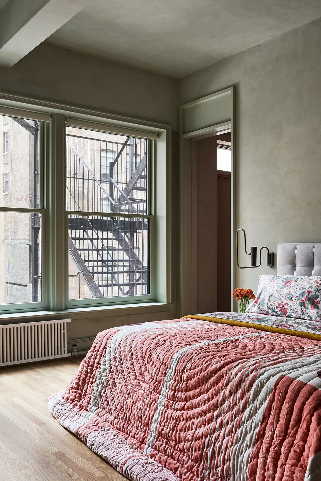 Cozy bedroom with a textured bedspread and a view of city buildings through large