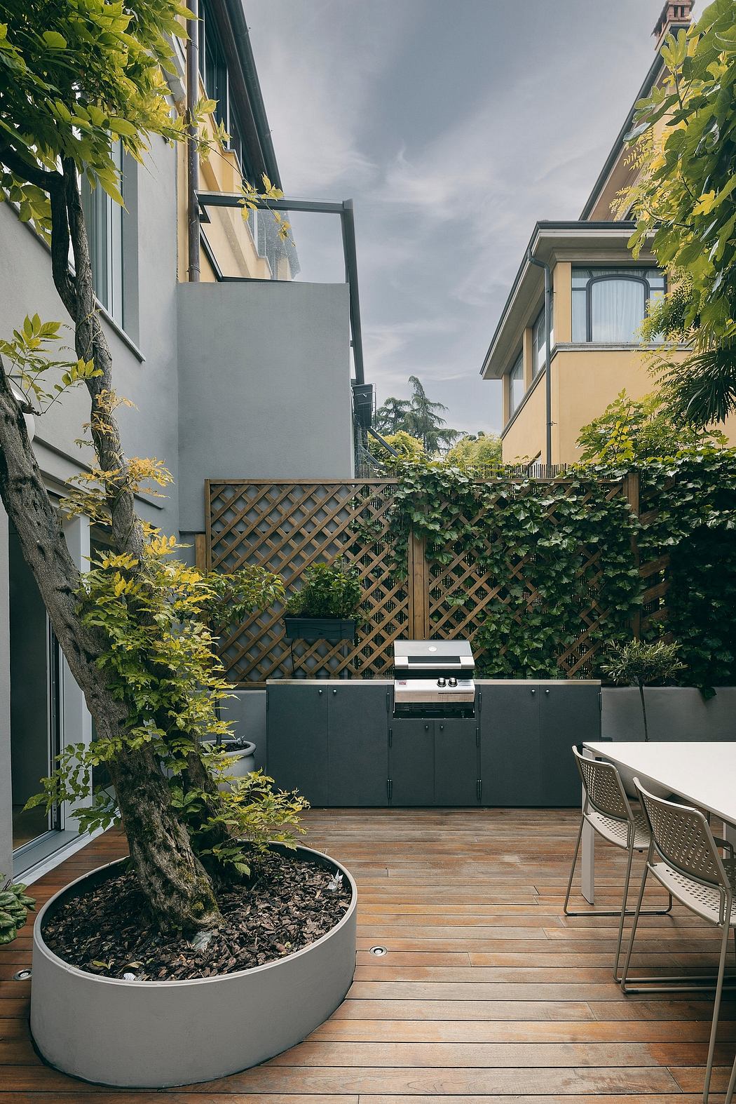 Contemporary courtyard with wood decking, potted tree, and outdoor dining setup.