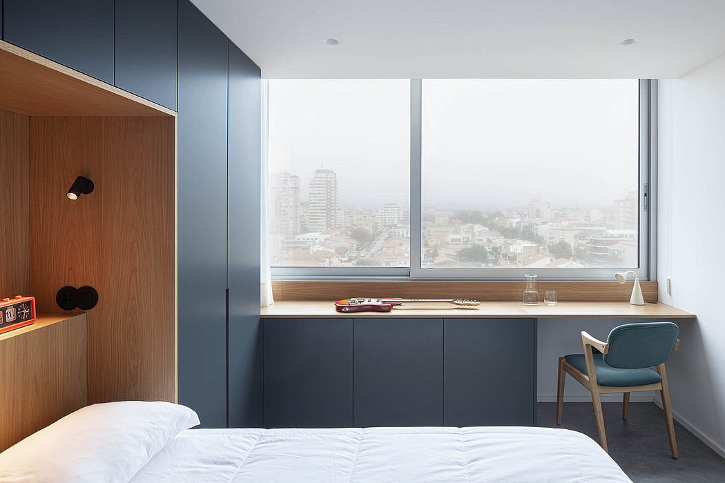 Sleek bedroom with large window, city view, minimal desk and wood accents