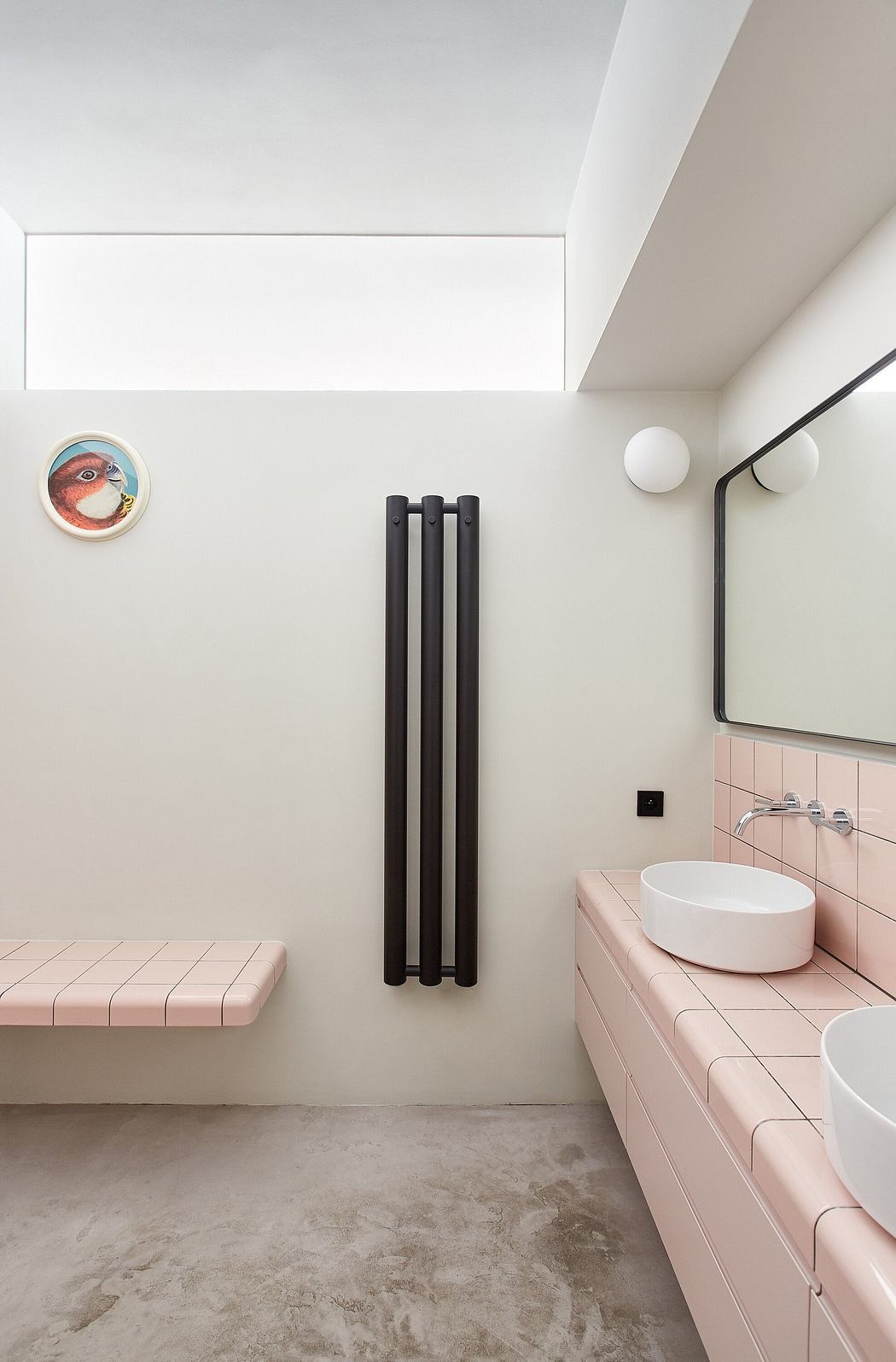 Modern bathroom with pink tiles, skylight, and black vertical radiator.
