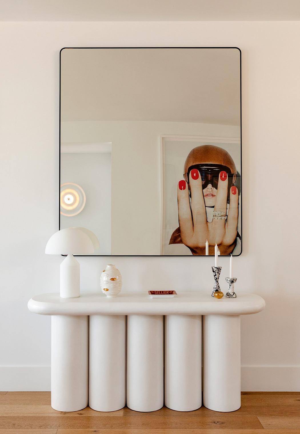Modern vanity with round mirror, unique cylindrical base, and minimalistic decor.