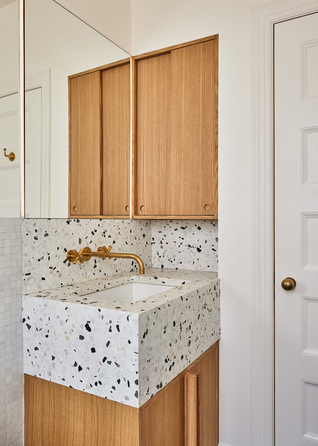 Modern bathroom with terrazzo sink and wooden cabinets.