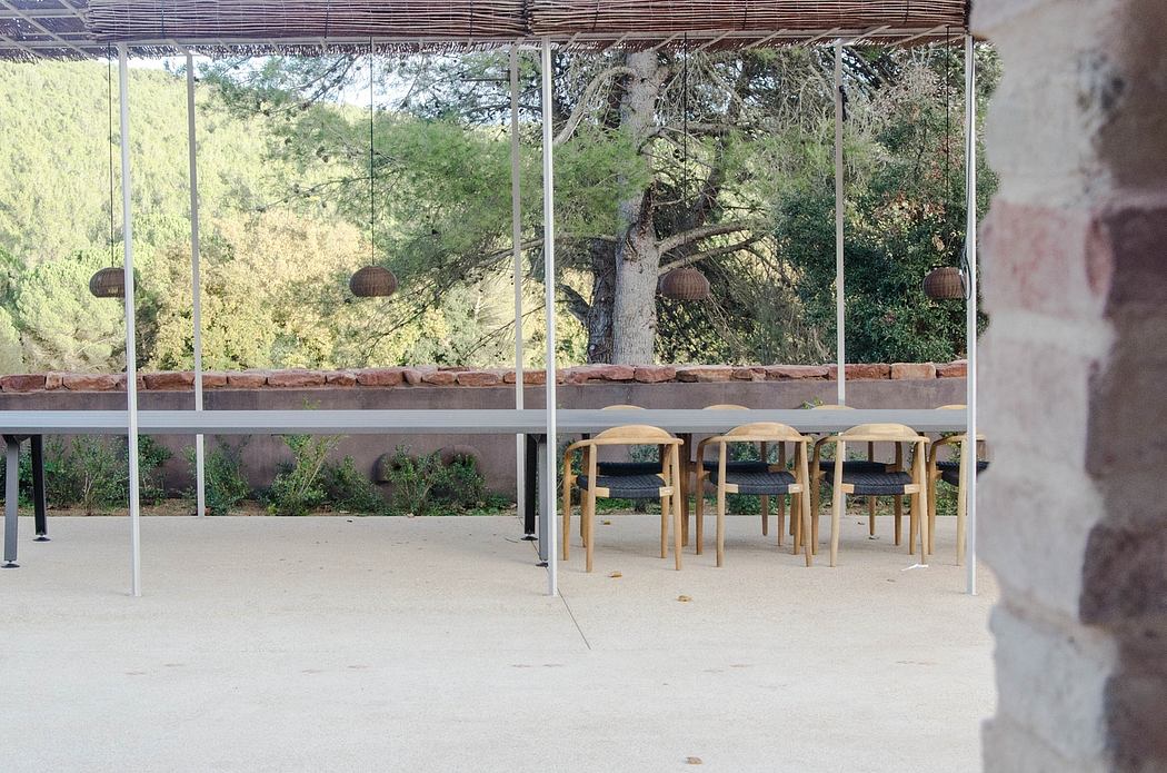Outdoor dining area with long table, benches, and hanging lights under a canopy.