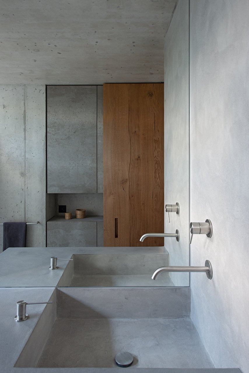 Minimalist bathroom with concrete sink and wooden door.