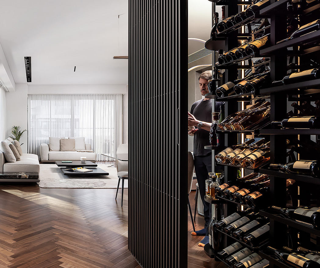 Modern living room with adjacent wine rack and person selecting a bottle.