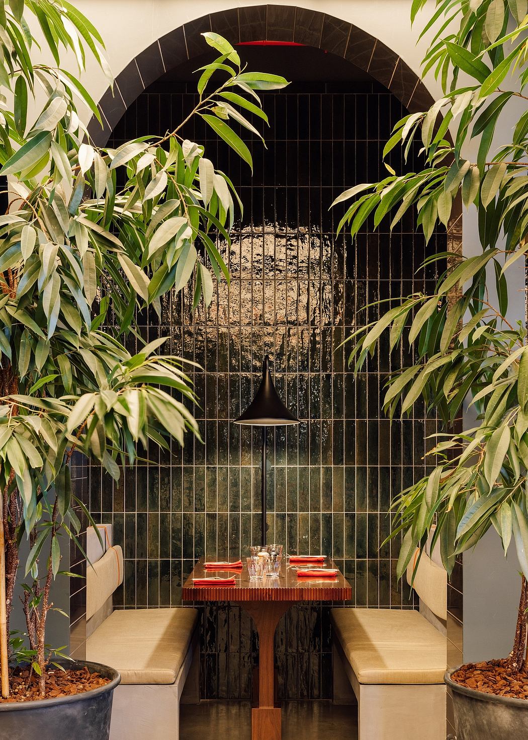 Cozy restaurant corner with bench seating, plants, and pendant light.