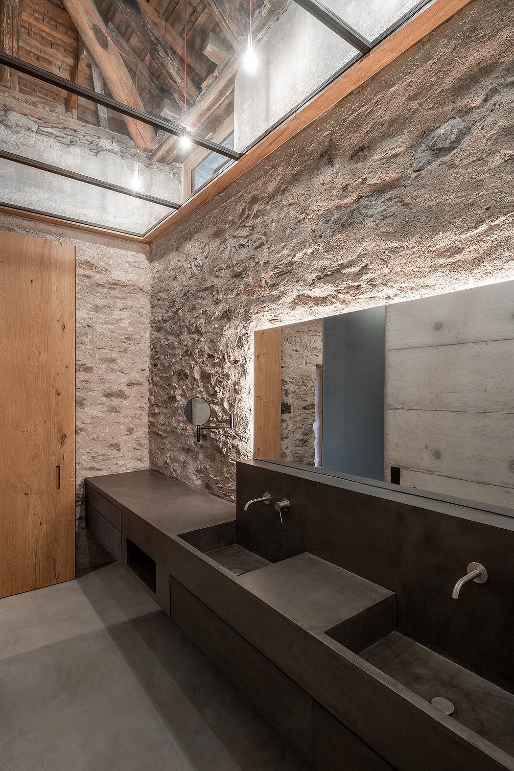 Rustic-chic bathroom with exposed stone walls and sleek concrete fixtures.