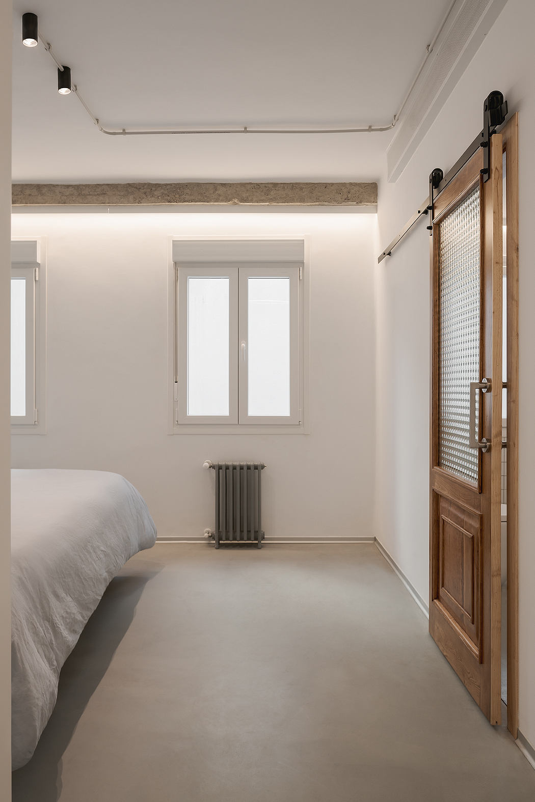 Minimalist bedroom with white walls, a bed to the left, a sliding door