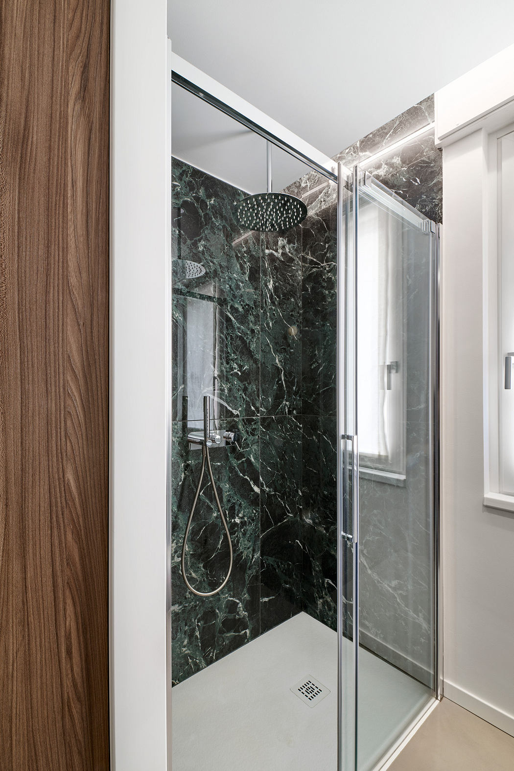 Contemporary bathroom with glass shower and green marble walls.