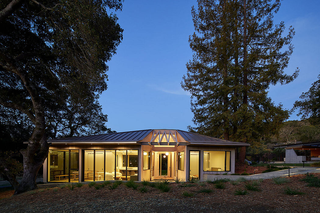 Modern house with illuminated interiors at twilight surrounded by trees.