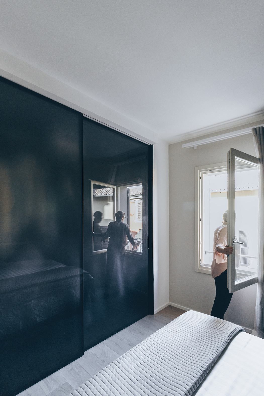 Sleek bedroom with black sliding door and person by window.