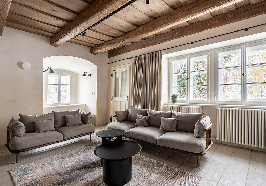 Elegant living room with exposed beams, grey sofas, and large windows.