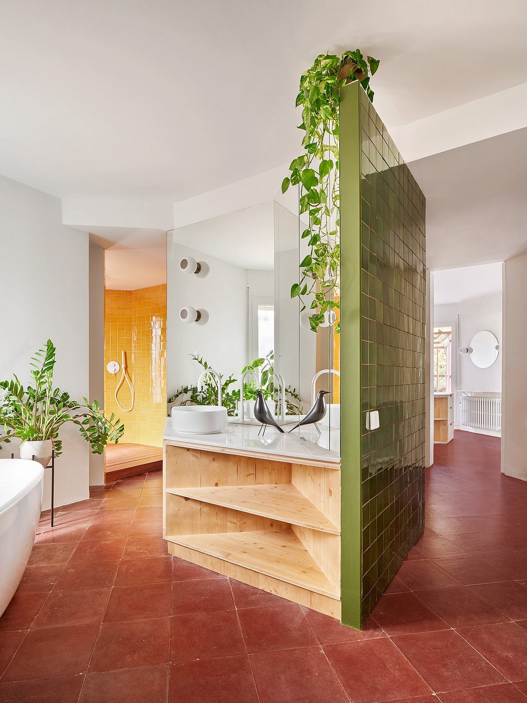 Bright bathroom with green tile partition, wooden vanity, and plants.