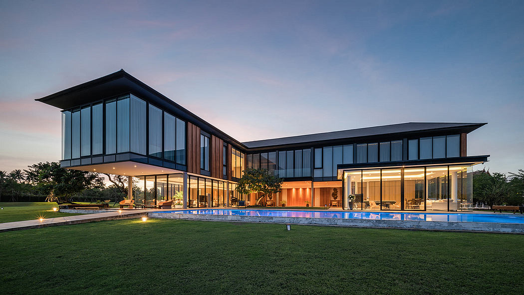 Contemporary house with large windows at dusk, overlooking a pool.