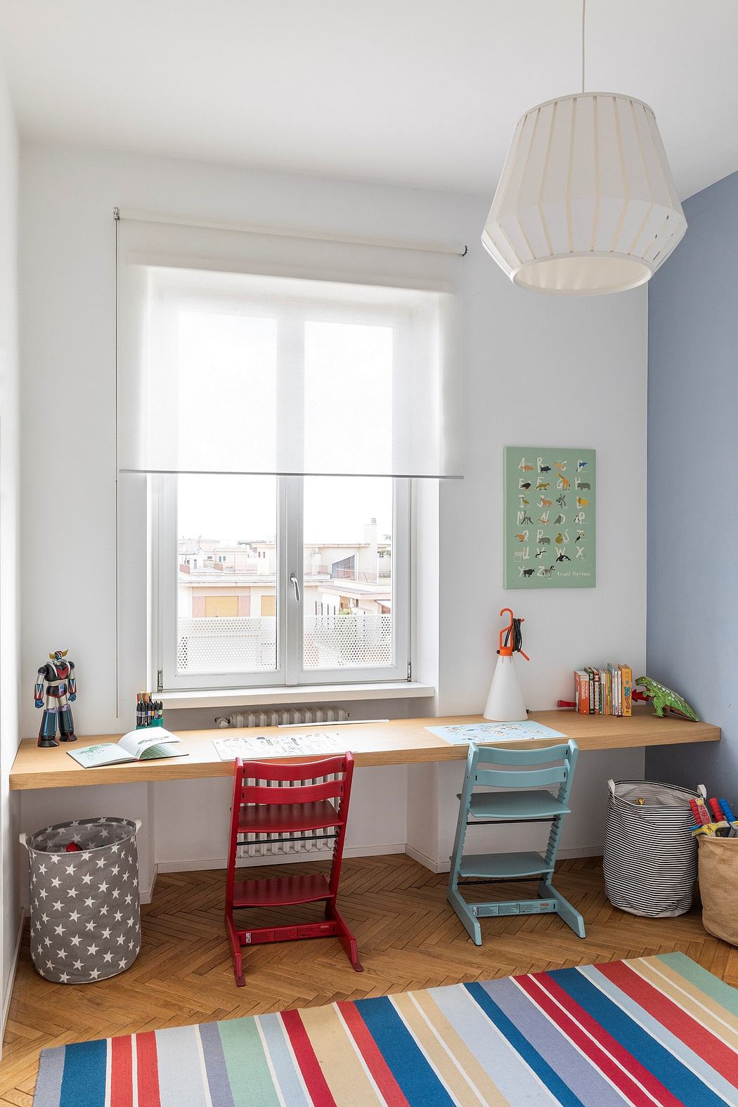 Bright study area with a striped rug, wooden desk, colorful chairs, and a