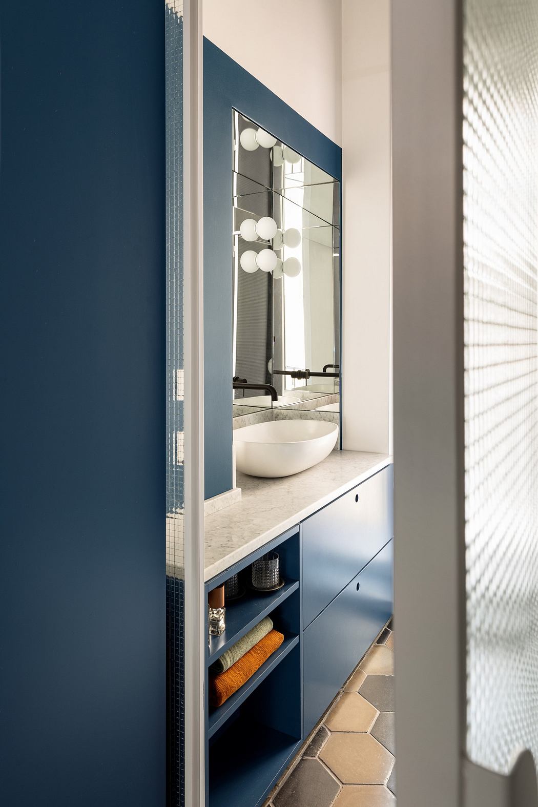 Modern bathroom vanity with blue cabinets and round mirror.