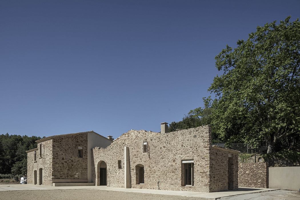 Contemporary stone building with arched entryway against clear sky.