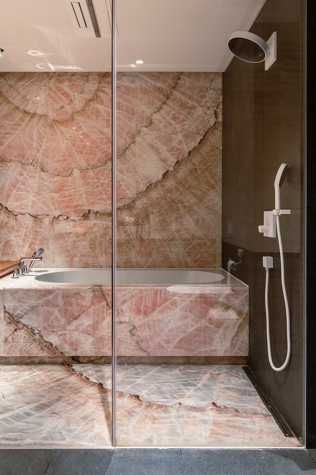 Chic bathroom with marble walls and glass shower partition.