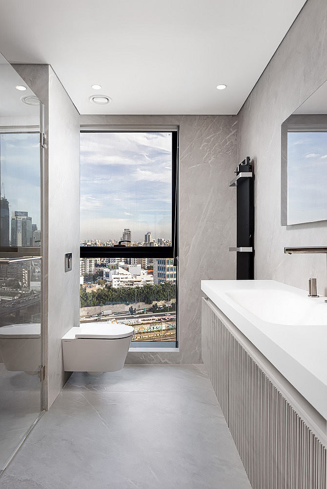 Modern bathroom with large window overlooking cityscape.