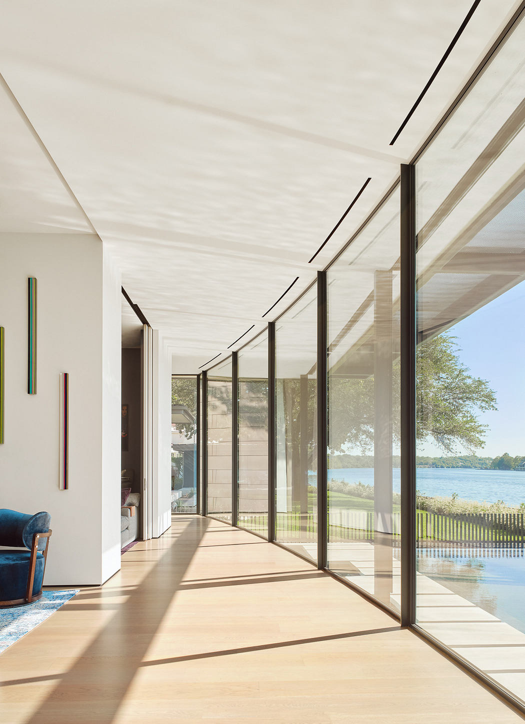 Modern corridor with floor-to-ceiling windows overlooking a lake.