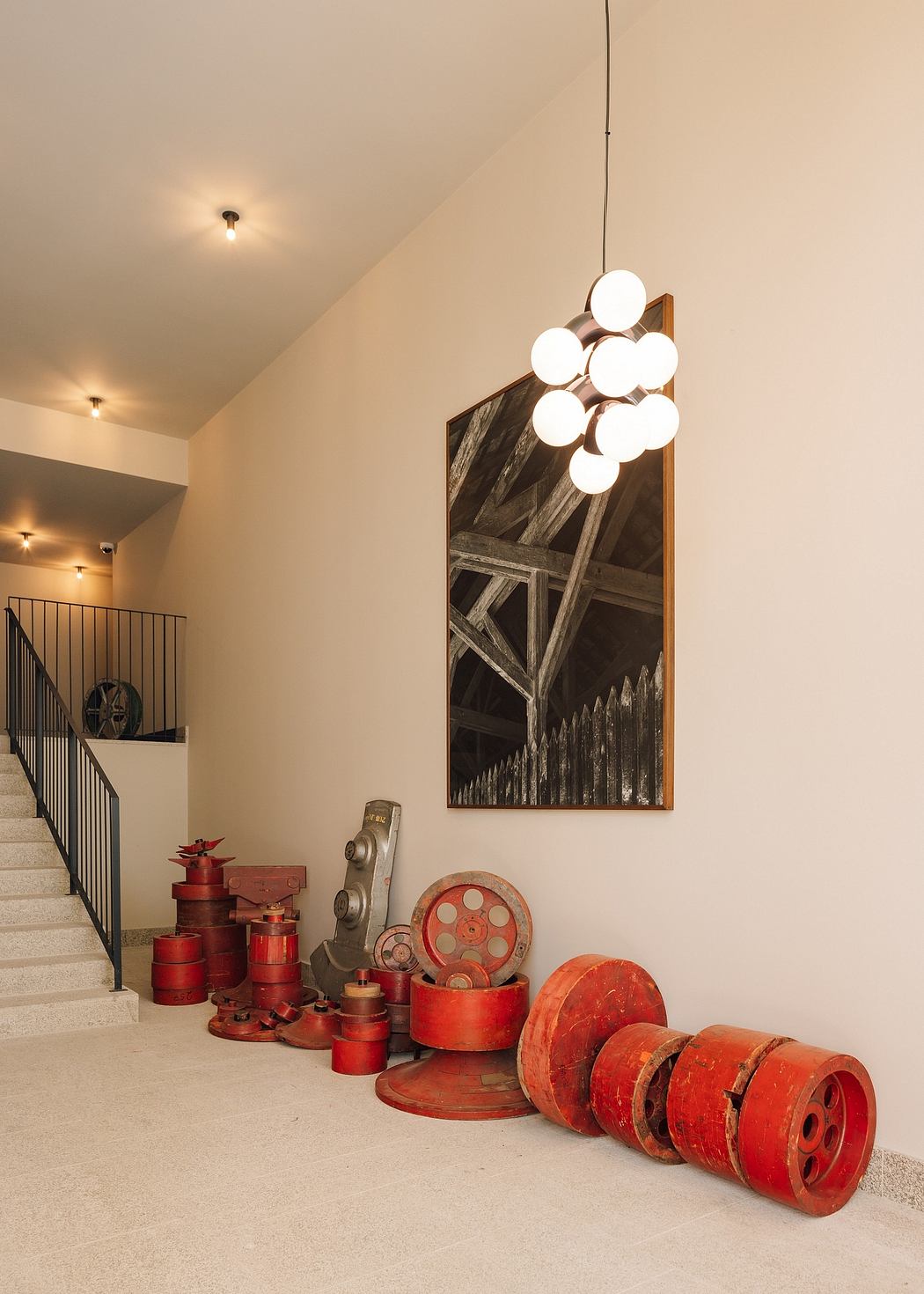 Staircase corner with film reels decor, modern light fixture, and art.
