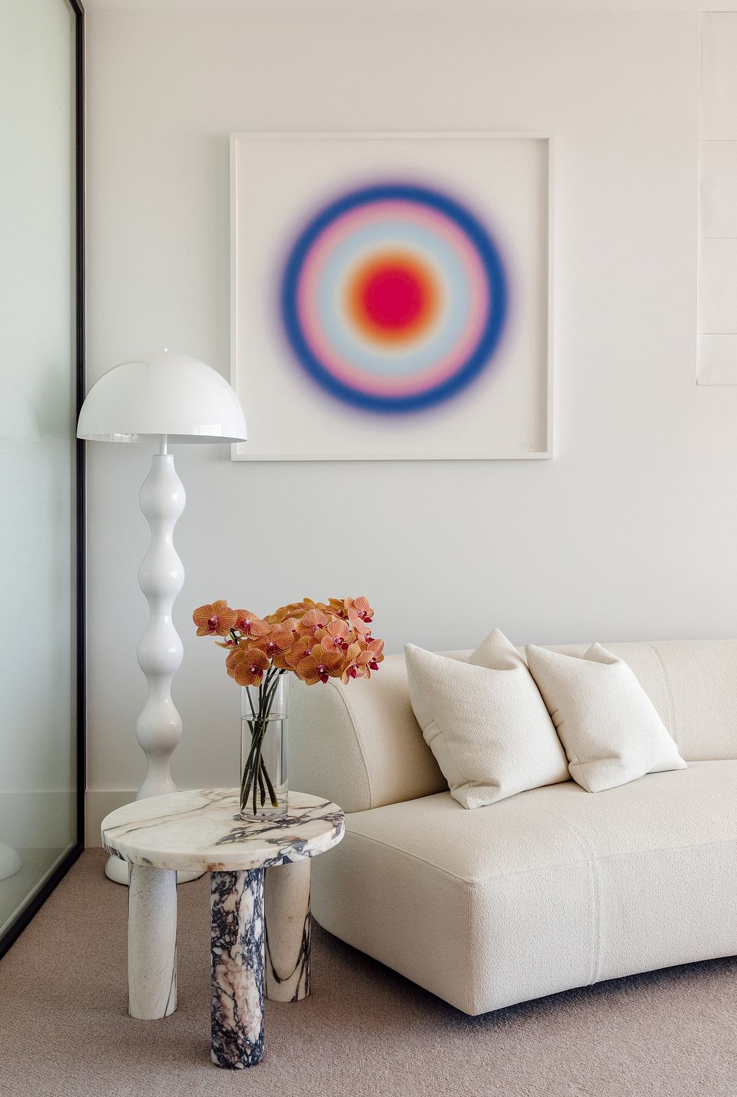 Modern living room with minimalist white sofa, abstract art, and unique side table lamp