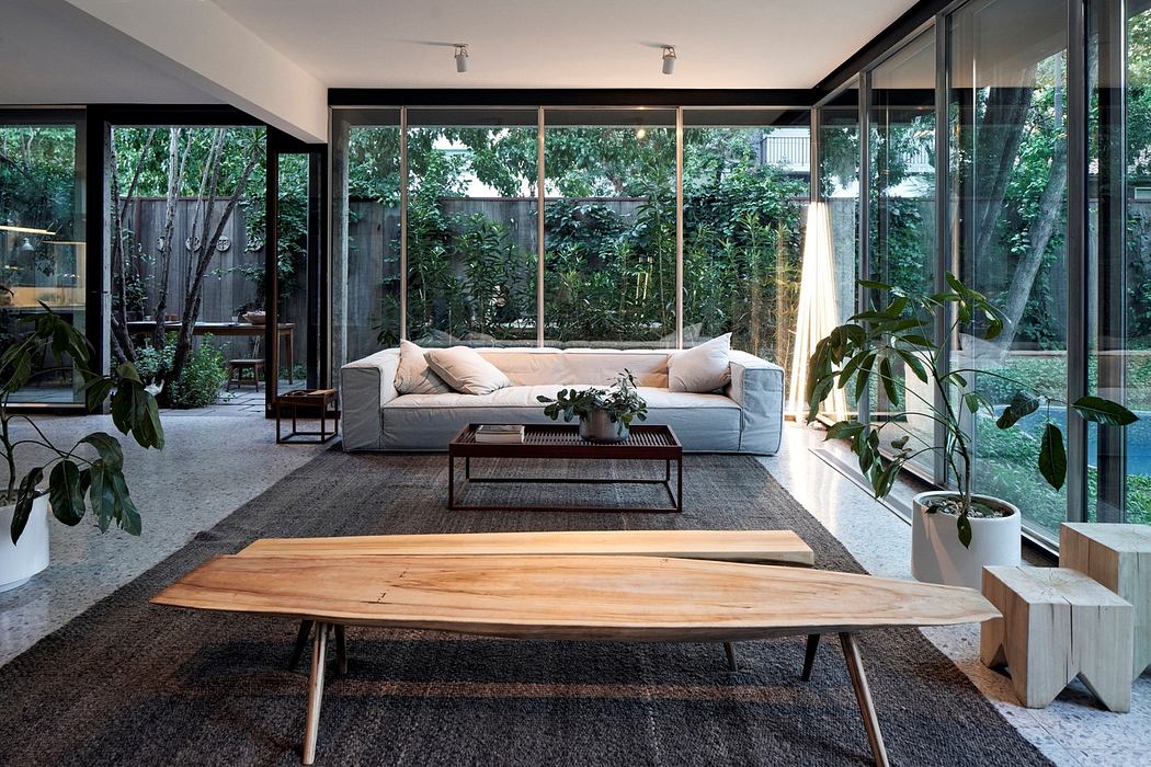 Modern living room with large glass windows, minimalist furniture, and indoor plants.