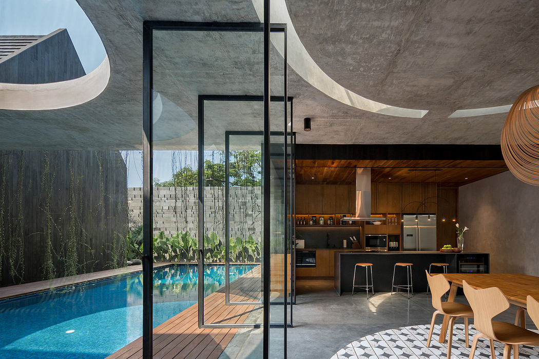 Modern kitchen with wooden accents viewed through glass doors beside an outdoor pool.