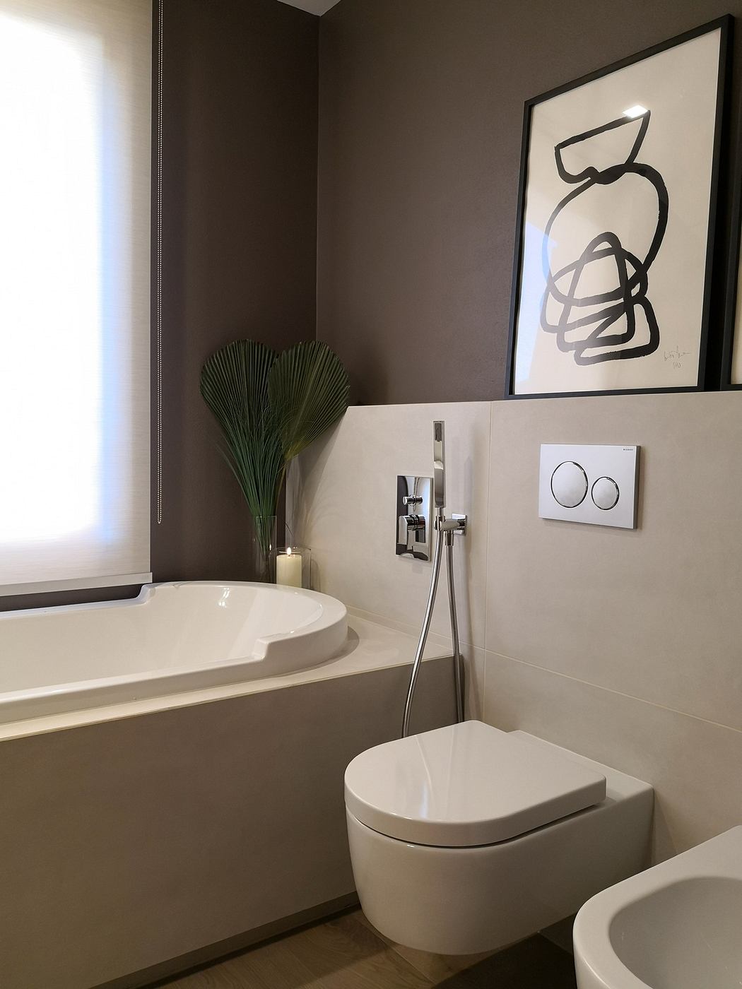 Contemporary bathroom with a sleek white bathtub, wall-mounted toilet, and abstract art