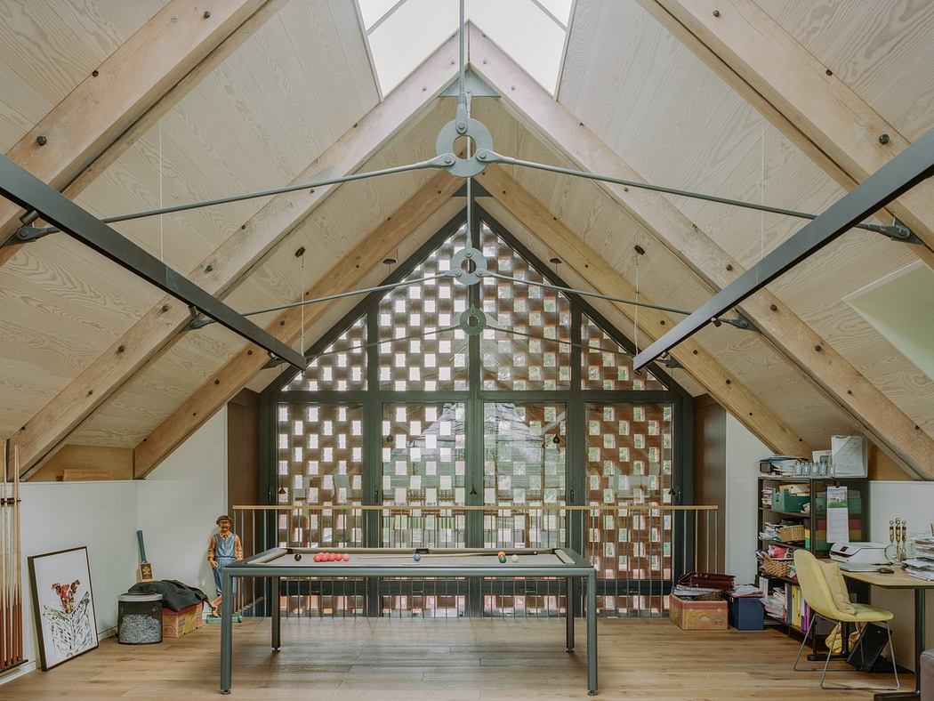 Spacious attic room with exposed wooden beams and large checkered window.