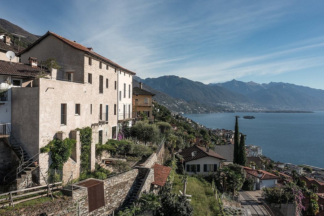 Hillside buildings overlooking a tranquil lake with mountains in the distance.