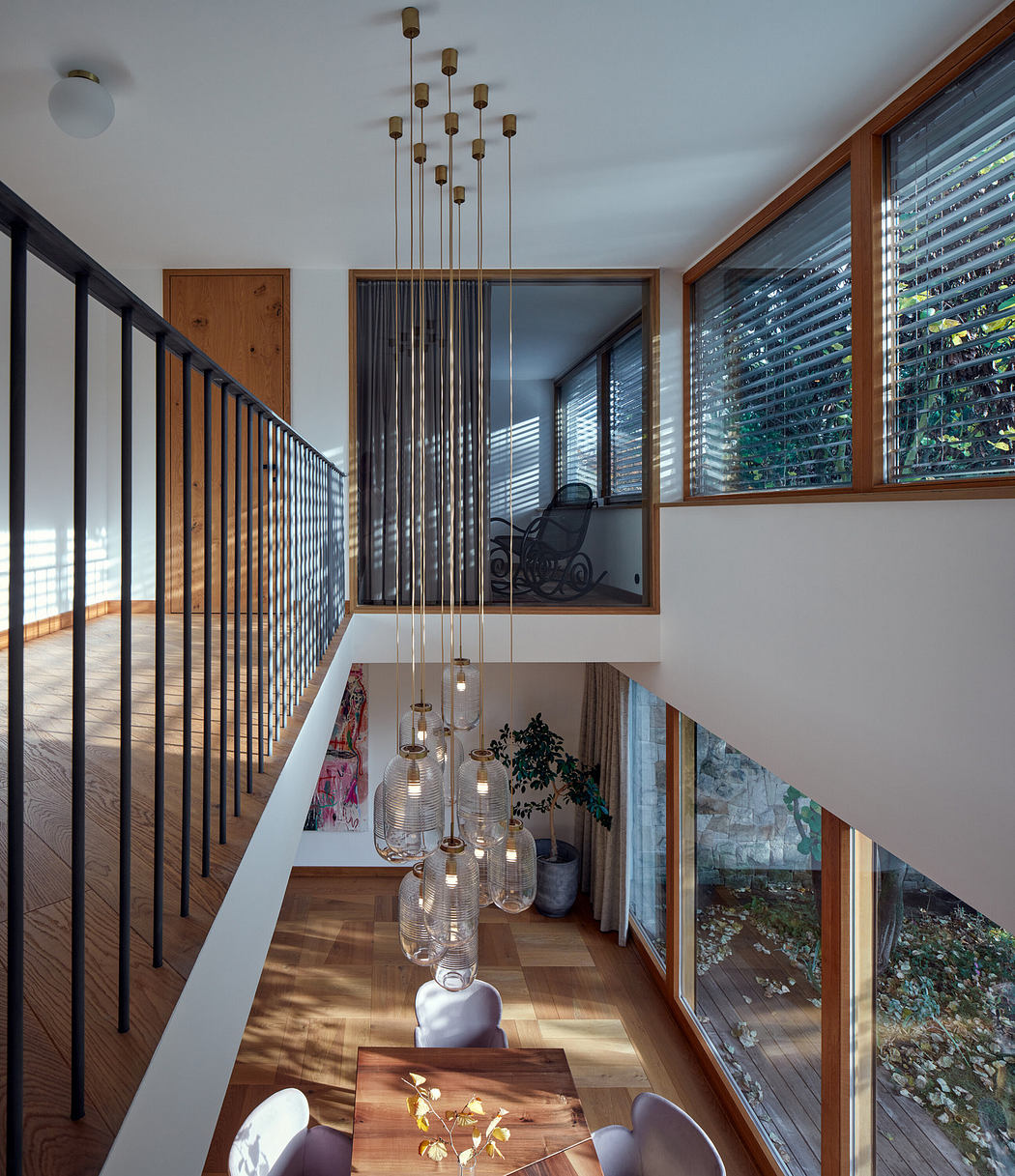 Modern two-level interior with wooden finishes, glass pendant lights, and a staircase.