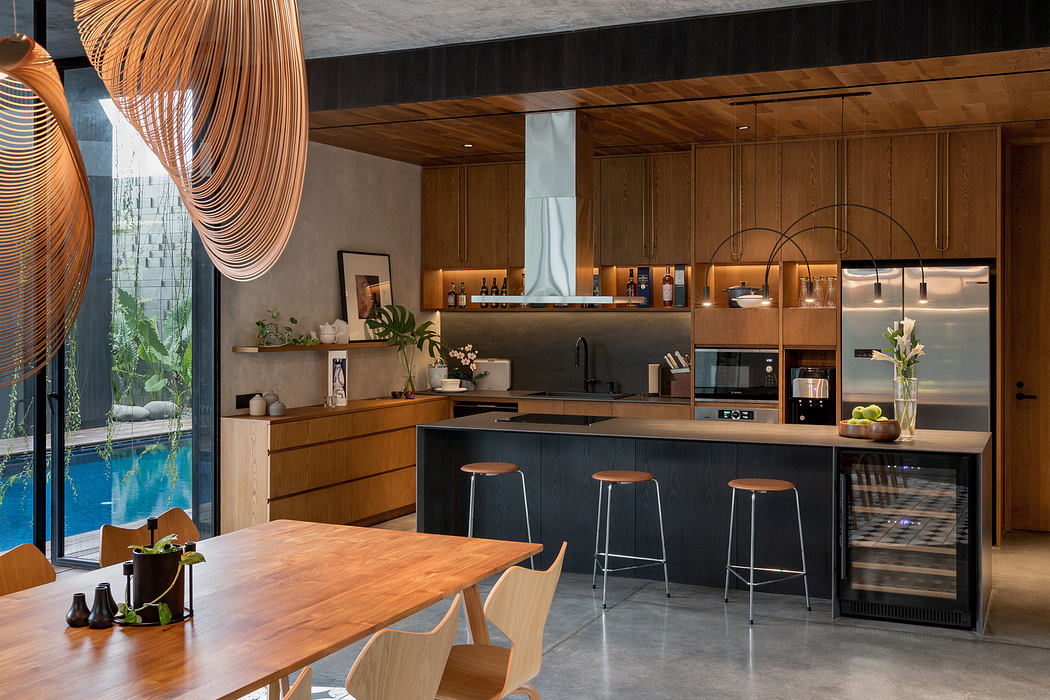 Modern kitchen with wooden cabinets, island, pendant lights, and adjacent dining area.