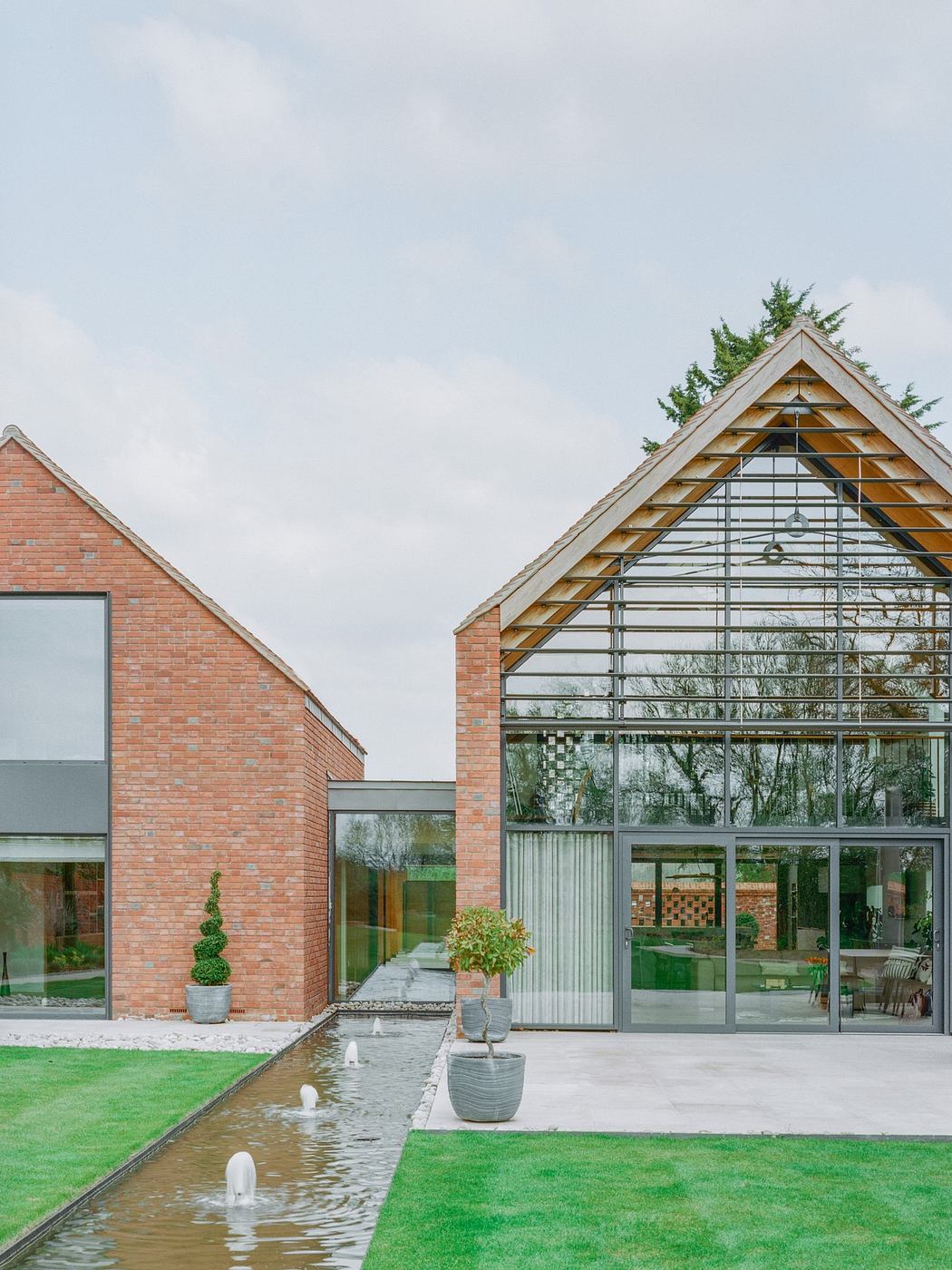 Modern brick house with large glass gable and garden water feature.
