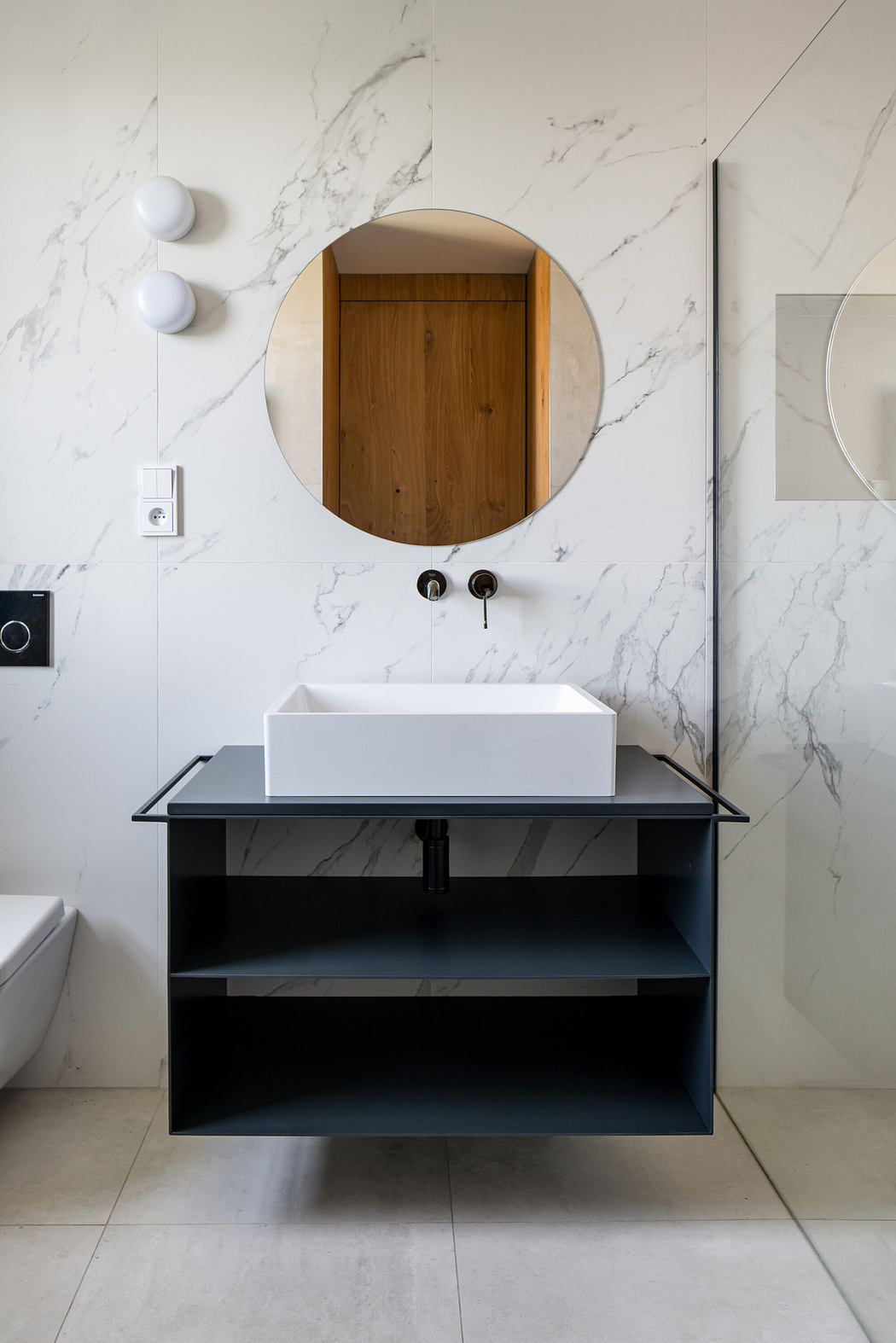 Modern bathroom with a round mirror, vessel sink, and black vanity.