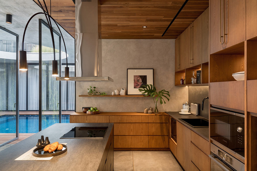 Modern kitchen interior with wooden cabinets and pool view.