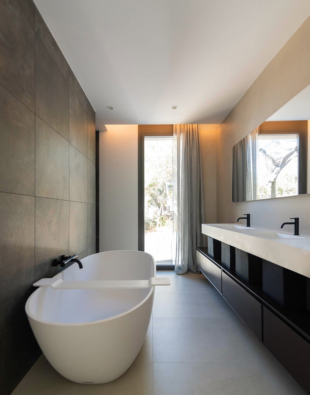 Modern bathroom with a freestanding tub, double vanity, and large window.