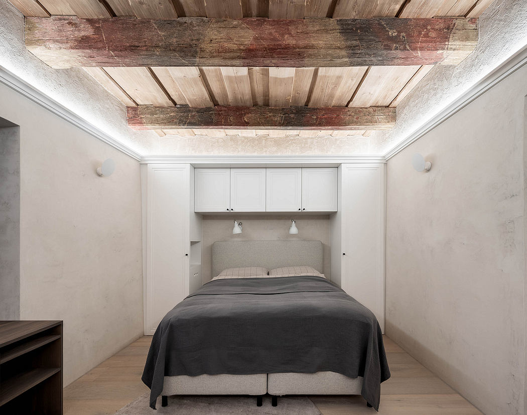 Minimalist bedroom with exposed wooden ceiling beams and built-in headboard.