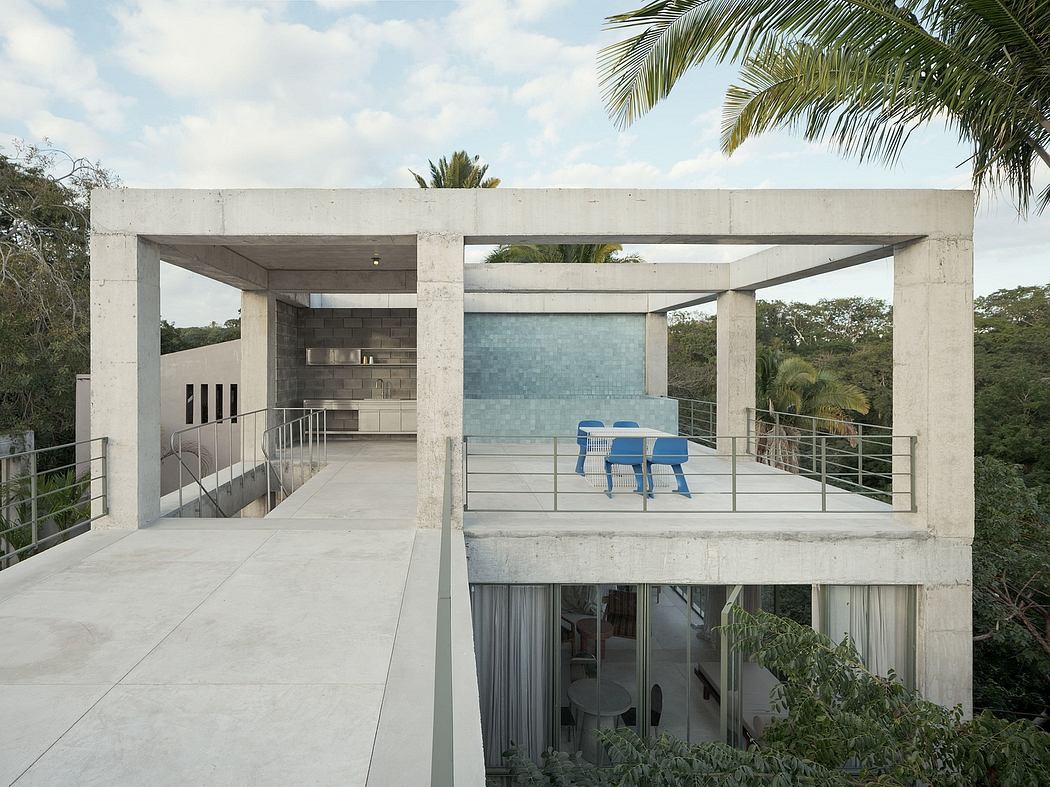 Modern concrete home with large terrace and blue chairs.
