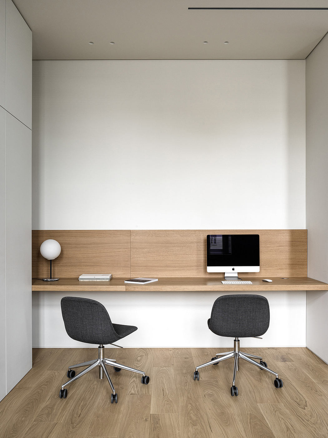 Minimalist home office with sleek wooden desk and two chairs.